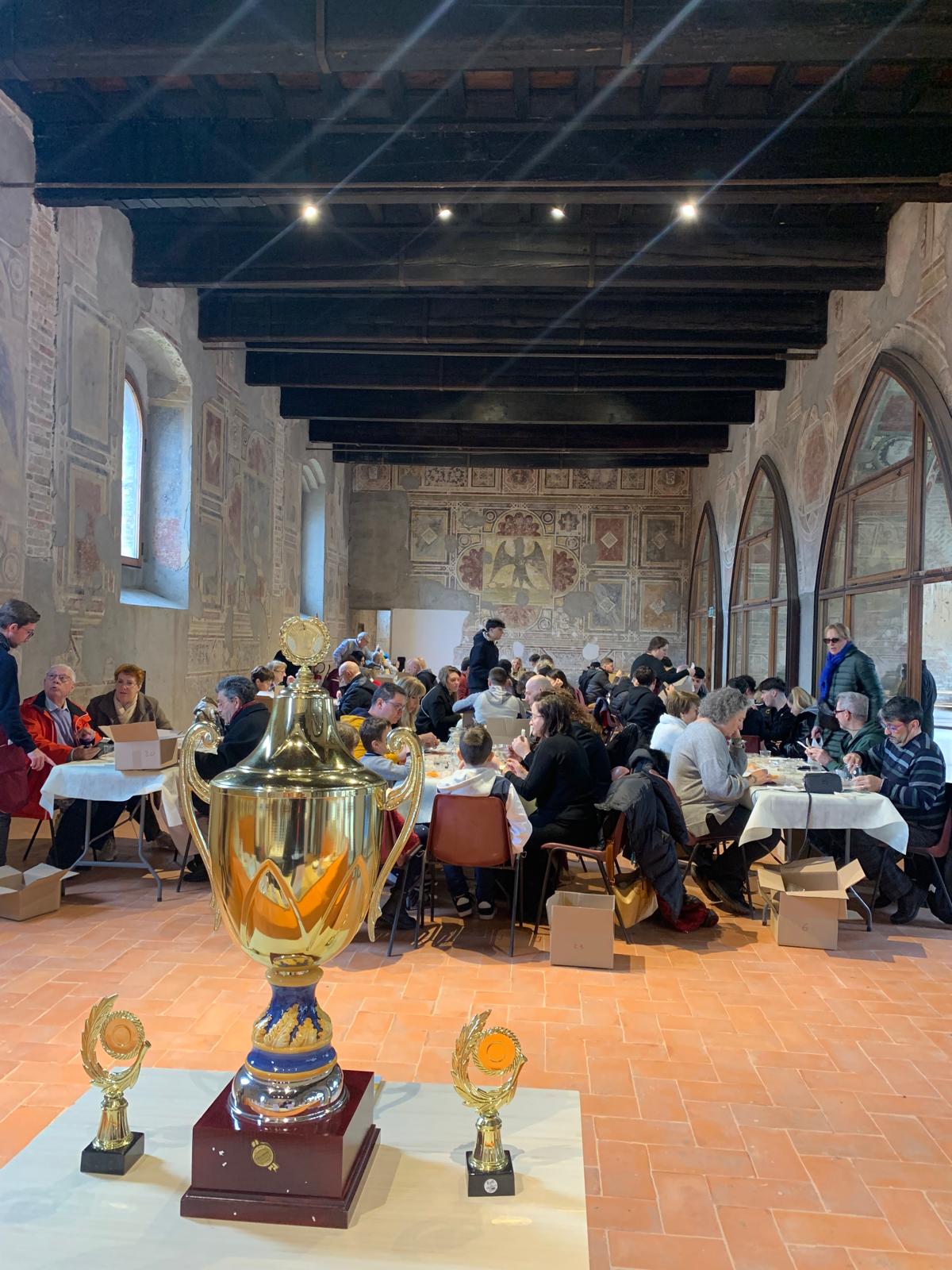 Coppa del Trofeo San Lucio e pubblico durante la degustazione nella sala del Castello di Pandino